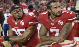 Colin Kapernick, (right) joined by one of his teammates, (left) pictured kneeling during the playing of the Star Spangled Banner.