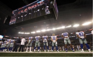 Pictured above are players of the Dallas Cowboys Football team. All are showing their respects to the playing of the National Anthem. (Picture via http://www.allposters.co.uk/-sp/Philadelphia-Eagles-and-Dallas-Cowboys-NFL-Dallas-Cowboys-stand-during-the-national-anthem-Posters_i935 9644_.htm)